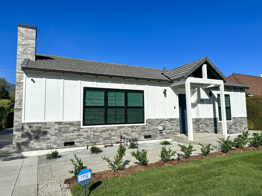 Cette image montre une façade de maison blanche rustique en planches et couvre-joints de plain-pied avec un revêtement mixte, un toit à quatre pans, un toit en tuile et un toit gris.