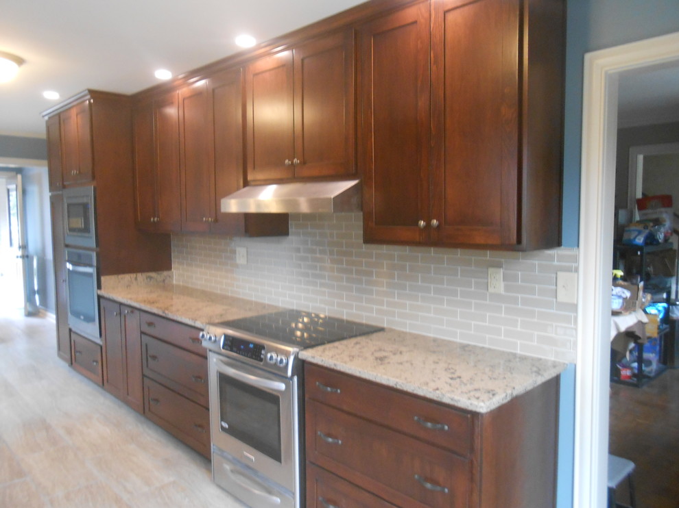 Example of a mid-sized transitional galley porcelain tile eat-in kitchen design with an undermount sink, shaker cabinets, dark wood cabinets, quartz countertops, beige backsplash, glass sheet backsplash, stainless steel appliances, blue walls and no island