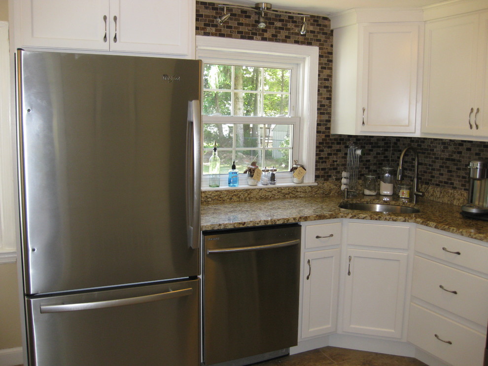 Example of a small transitional l-shaped porcelain tile and brown floor kitchen design in Boston with an undermount sink, recessed-panel cabinets, white cabinets, granite countertops, brown backsplash, stainless steel appliances, no island, glass tile backsplash and beige countertops