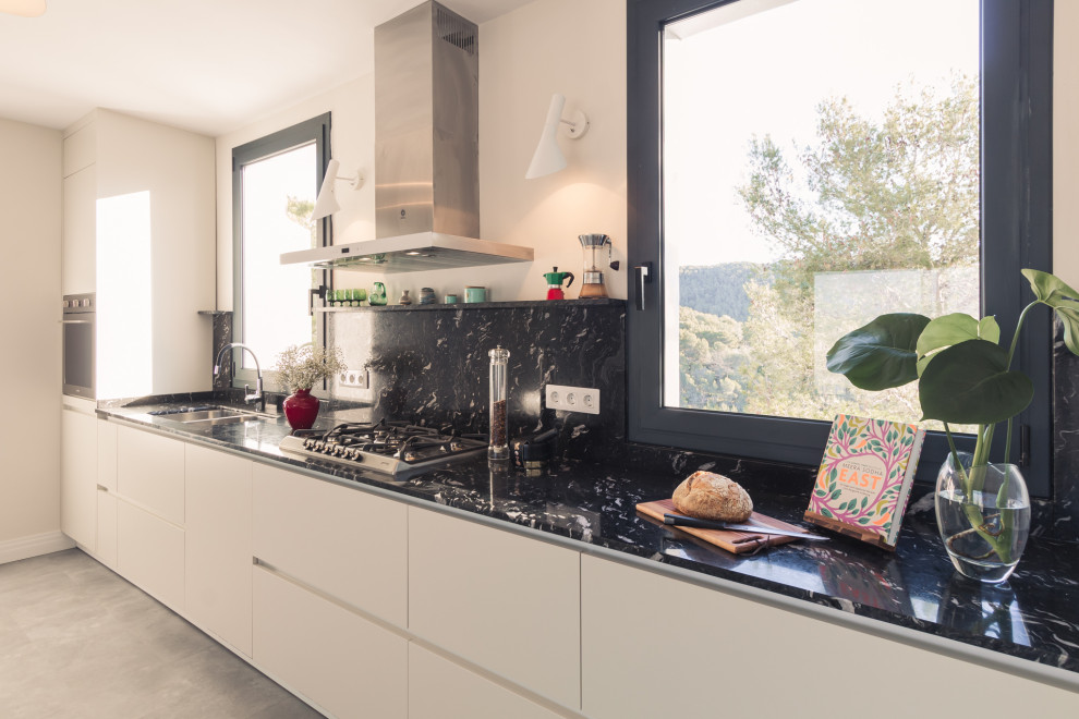 Foto på ett mycket stort funkis svart linjärt kök med öppen planlösning, med en undermonterad diskho, släta luckor, beige skåp, granitbänkskiva, svart stänkskydd, integrerade vitvaror, vinylgolv och grått golv