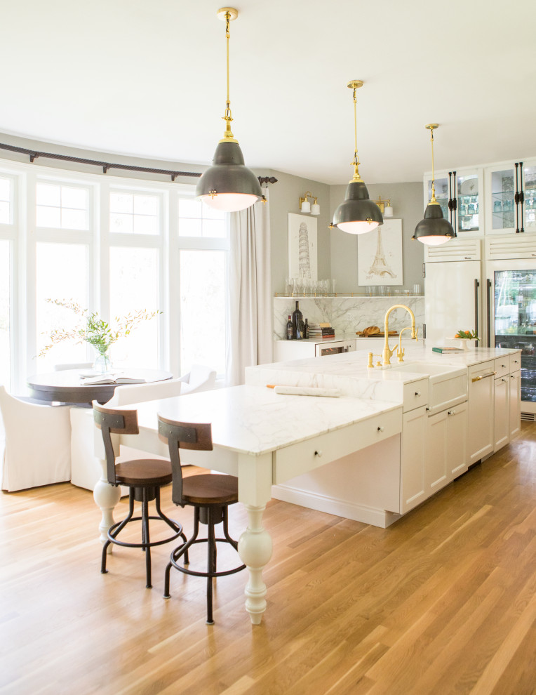 Inspiration for a medium sized l-shaped kitchen/diner in Seattle with a belfast sink, glass-front cabinets, yellow cabinets, marble worktops, white splashback, porcelain splashback, white appliances, medium hardwood flooring, an island, brown floors, white worktops and a drop ceiling.