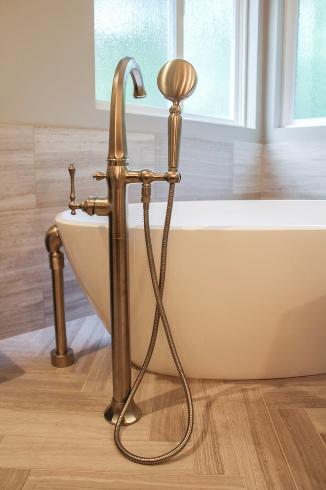 Freestanding bathtub - large transitional master limestone tile limestone floor and beige floor freestanding bathtub idea in Denver with brown cabinets, quartz countertops, a hinged shower door, shaker cabinets, gray walls and an undermount sink