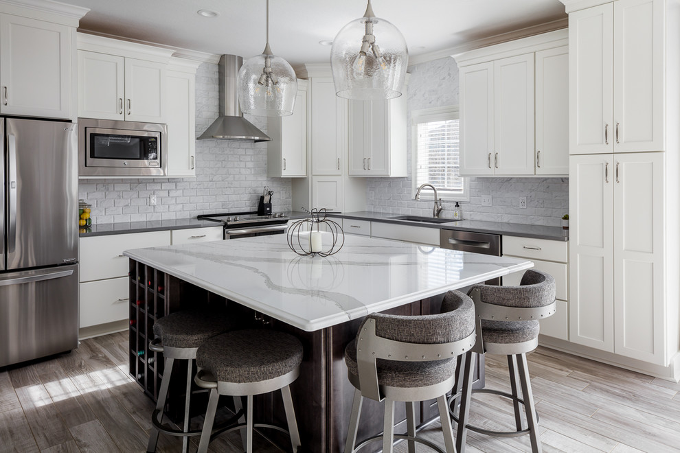 Inspiration for a mid-sized transitional l-shaped kitchen in Other with an undermount sink, shaker cabinets, white cabinets, quartz benchtops, white splashback, marble splashback, stainless steel appliances, ceramic floors, with island, grey floor and grey benchtop.