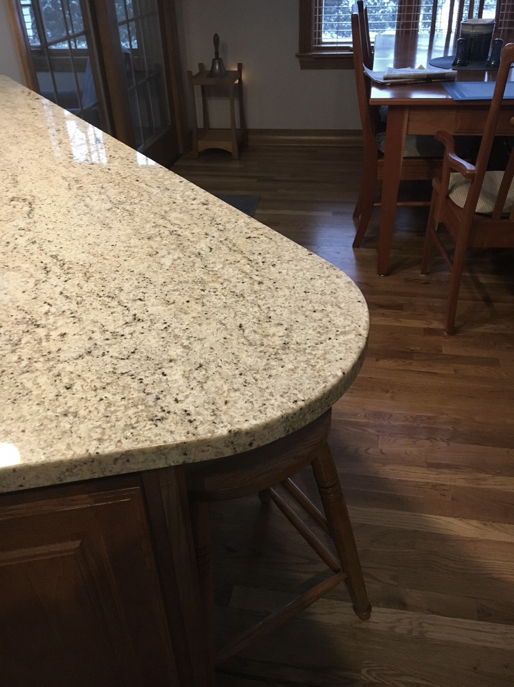 Inspiration for a large transitional u-shaped medium tone wood floor eat-in kitchen remodel with an undermount sink, raised-panel cabinets, medium tone wood cabinets, granite countertops, white backsplash, ceramic backsplash, stainless steel appliances and an island