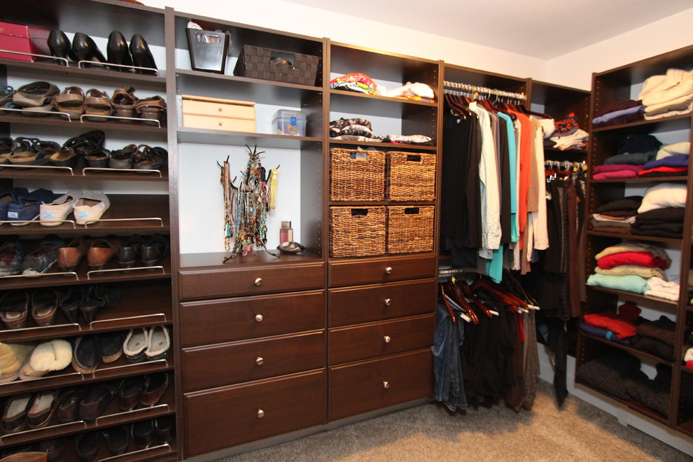 This is an example of a mid-sized traditional gender-neutral walk-in wardrobe in Grand Rapids with carpet, raised-panel cabinets and medium wood cabinets.