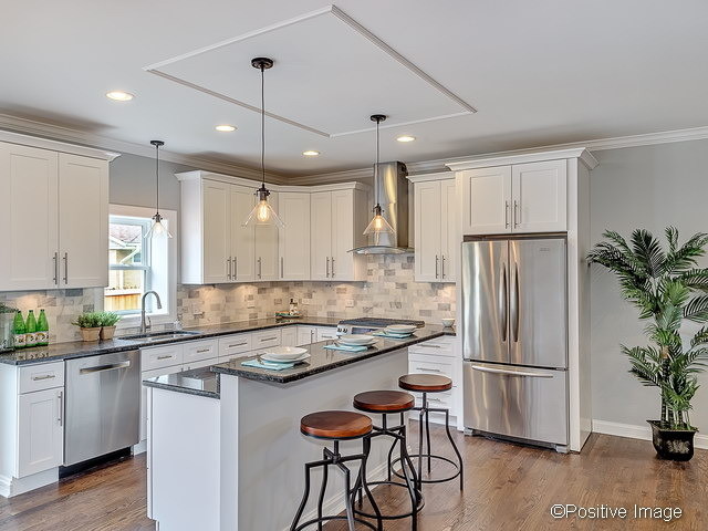 Eat-in kitchen - large transitional l-shaped medium tone wood floor eat-in kitchen idea in Chicago with recessed-panel cabinets, white cabinets, quartzite countertops, gray backsplash, stainless steel appliances and an island