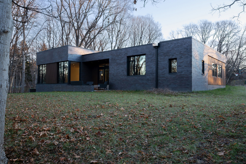 Modelo de fachada de casa multicolor y negra minimalista de una planta con revestimiento de ladrillo y tejado plano