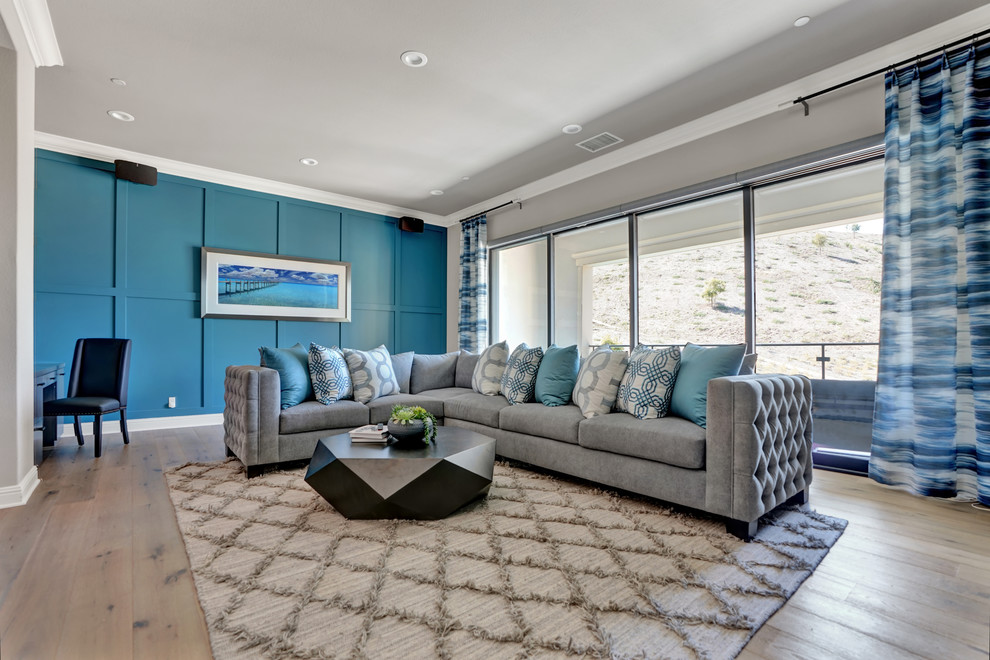 This is an example of a mid-sized contemporary loft-style family room in Orange County with grey walls, light hardwood floors, a wall-mounted tv and brown floor.