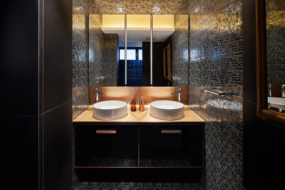 Inspiration for a mid-sized contemporary powder room in Singapore with flat-panel cabinets, black cabinets, black tile, black walls, a vessel sink, multi-coloured floor, beige benchtops and a floating vanity.