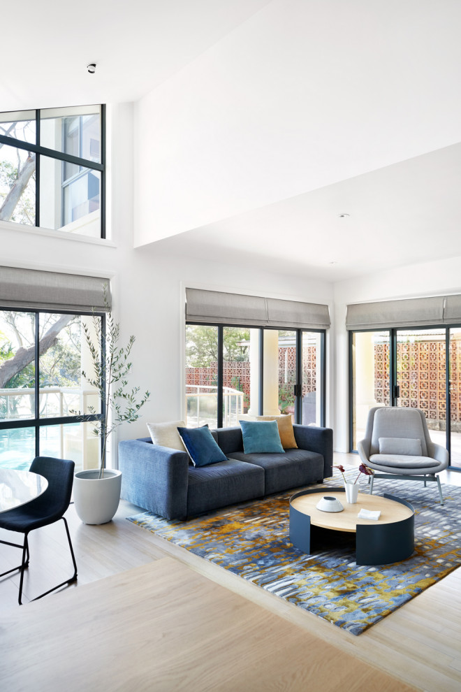 This is an example of a mid-sized contemporary open concept living room in Sydney with white walls, no fireplace, light hardwood floors and beige floor.