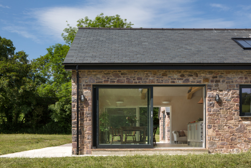 Photo of a large country front house exterior in Devon with stone cladding and a pitched roof.
