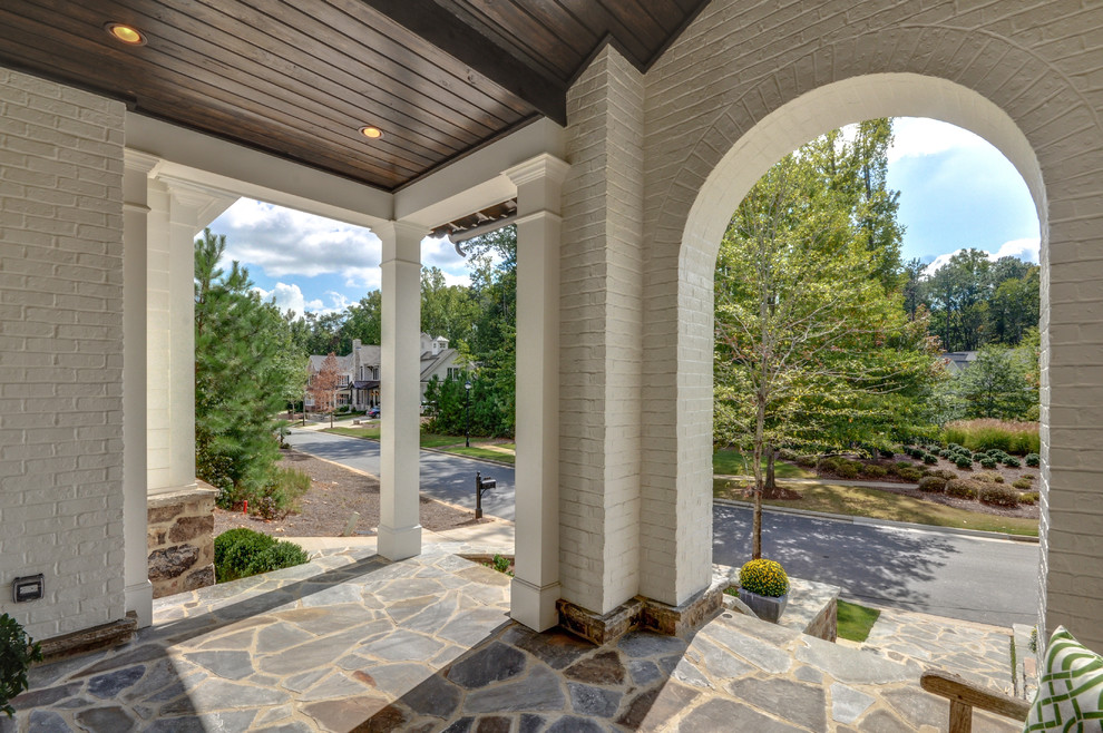 Contemporary front yard verandah in Atlanta with natural stone pavers and a roof extension.