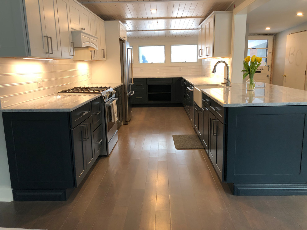 Design ideas for a large midcentury l-shaped eat-in kitchen in New York with a farmhouse sink, shaker cabinets, blue cabinets, granite benchtops, white splashback, subway tile splashback, stainless steel appliances, light hardwood floors, no island, grey floor, grey benchtop and wood.