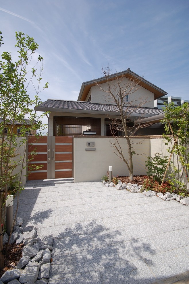 This is an example of a large asian two-storey grey house exterior in Nagoya with mixed siding, a gable roof and a tile roof.