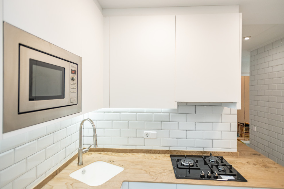 Idéer för ett mellanstort medelhavsstil brun kök, med en enkel diskho, släta luckor, vita skåp, träbänkskiva, vitt stänkskydd, stänkskydd i keramik, rostfria vitvaror, klinkergolv i keramik och blått golv