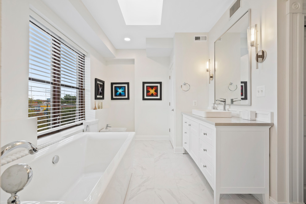 Design ideas for a modern master bathroom in Baltimore with white cabinets, a freestanding tub, an alcove shower, a bidet, white tile, ceramic tile, beige walls, ceramic floors, a trough sink, quartzite benchtops, a hinged shower door, grey benchtops, a niche and a double vanity.