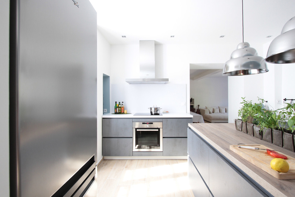 Large contemporary kitchen in Paris with an undermount sink, wood benchtops, white splashback, stainless steel appliances, light hardwood floors and multiple islands.