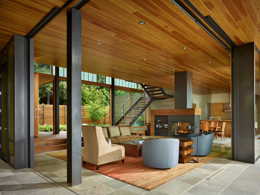 This is an example of a contemporary open concept living room in Seattle with beige walls and a two-sided fireplace.
