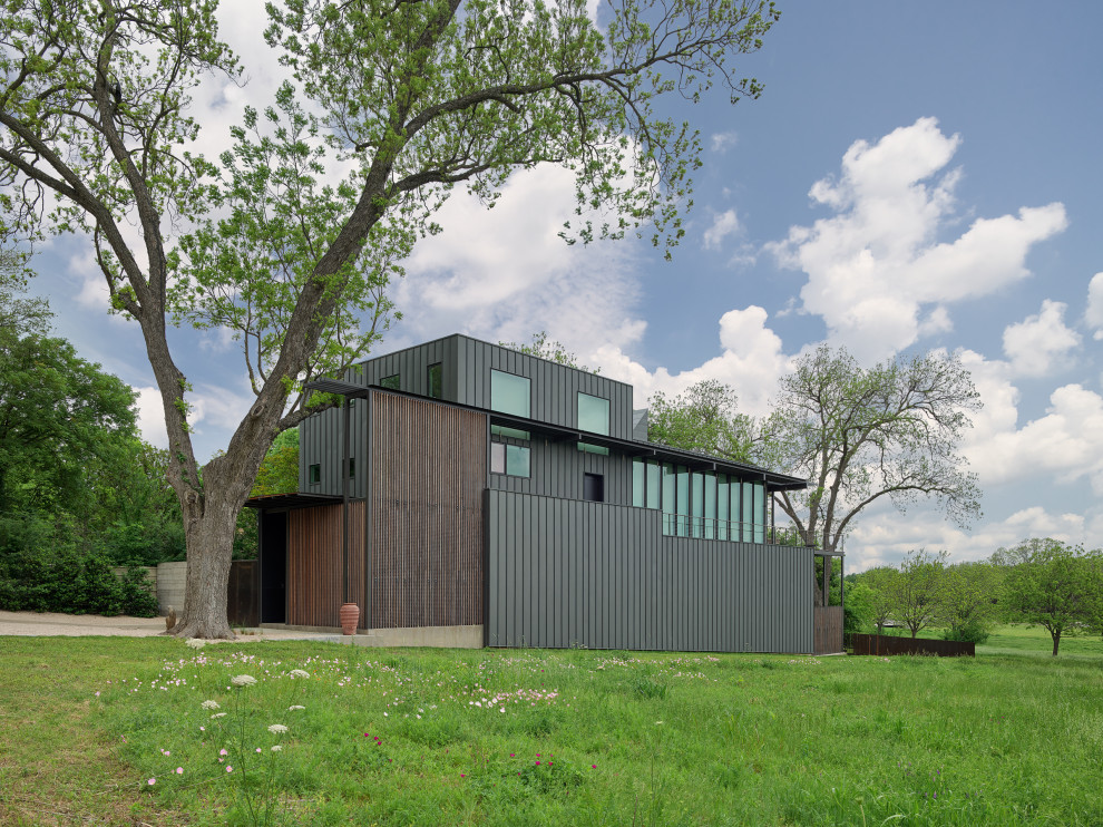 На фото: большой, трехэтажный, серый частный загородный дом в стиле модернизм с облицовкой из металла, плоской крышей, металлической крышей, серой крышей и отделкой доской с нащельником с