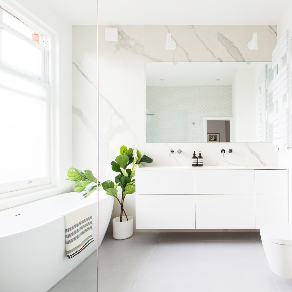 Design ideas for a large modern master wet room bathroom with flat-panel cabinets, white cabinets, a freestanding tub, a wall-mount toilet, yellow tile, marble, white walls, concrete floors, an integrated sink, solid surface benchtops, grey floor and white benchtops.