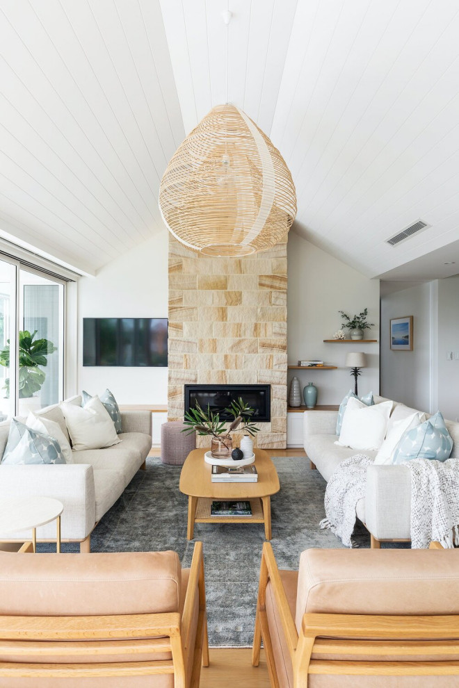 Großes, Offenes Maritimes Wohnzimmer mit weißer Wandfarbe, braunem Holzboden, Kamin, Kaminumrandung aus gestapelten Steinen, TV-Wand, beigem Boden, Holzdielendecke und Wandpaneelen in Sydney