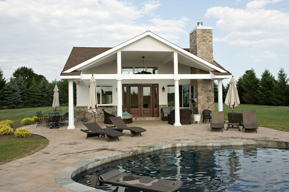 Design ideas for a mid-sized traditional backyard custom-shaped pool in New York with a pool house and concrete pavers.