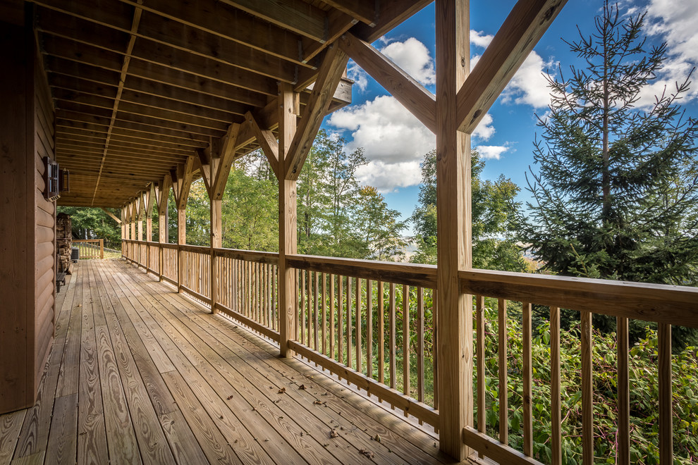 Huge mountain style backyard deck photo in Charlotte with a roof extension