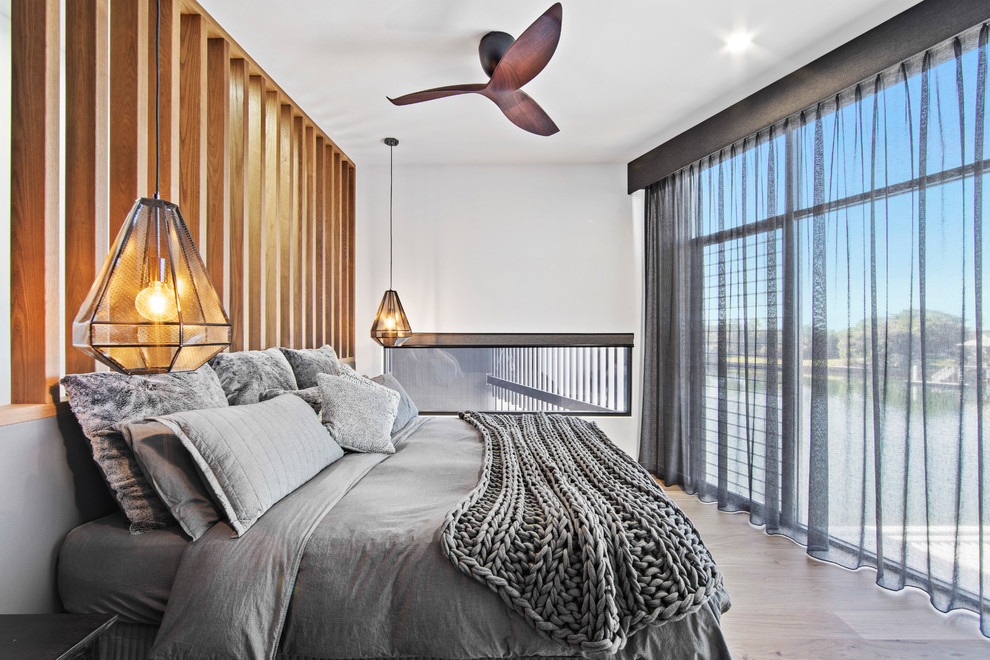 Contemporary bedroom in Sunshine Coast with white walls, light hardwood floors and grey floor.
