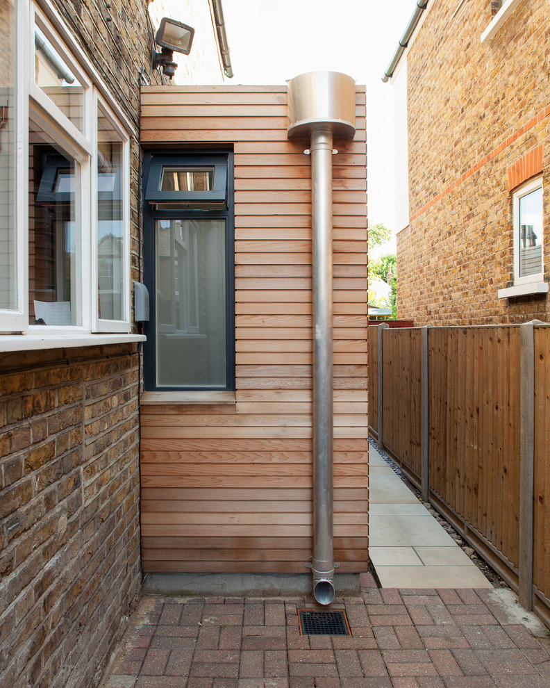 This is an example of a mid-sized contemporary one-storey brown exterior in London with wood siding and a flat roof.