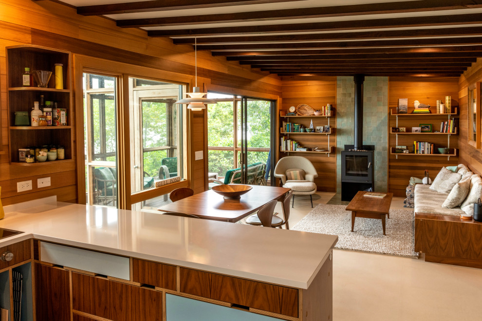 Идея дизайна: гостиная комната в стиле ретро с коричневыми стенами, бетонным полом, печью-буржуйкой, фасадом камина из плитки, бежевым полом, балками на потолке и деревянными стенами
