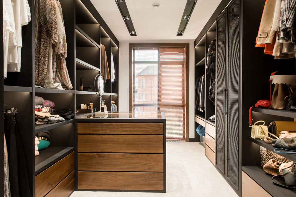 Contemporary gender-neutral walk-in wardrobe in Moscow with louvered cabinets, black cabinets and beige floor.
