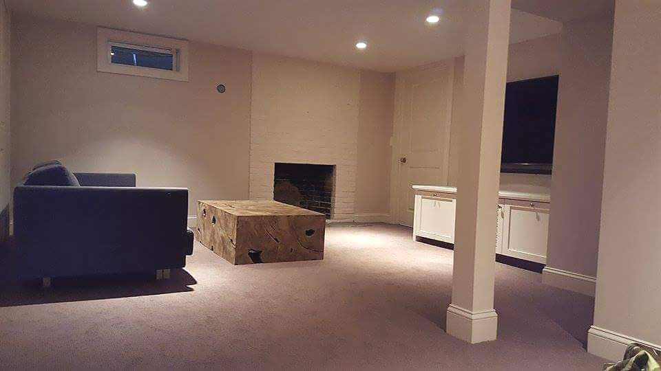 Basement - mid-sized transitional underground carpeted and beige floor basement idea with black walls, a standard fireplace and a brick fireplace