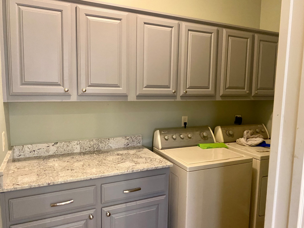 Inspiration for a mid-sized galley dedicated laundry room in Other with a drop-in sink, shaker cabinets, grey cabinets, quartz benchtops, white splashback, subway tile splashback, green walls, laminate floors, a side-by-side washer and dryer, brown floor and white benchtop.