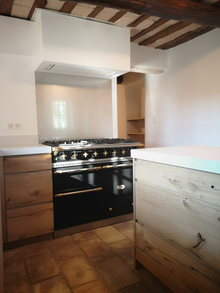 Photo of a small transitional l-shaped separate kitchen in Other with an undermount sink, beaded inset cabinets, light wood cabinets, quartz benchtops, metallic splashback, metal splashback, black appliances, terra-cotta floors, with island, pink floor and white benchtop.