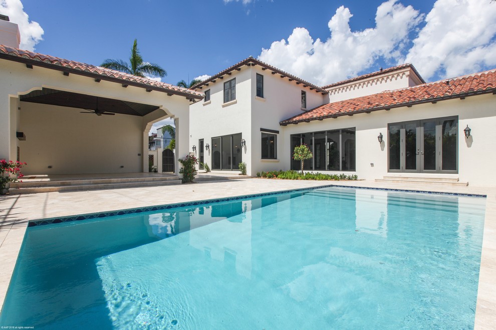 Photo of a large mediterranean backyard rectangular pool in Miami with natural stone pavers.