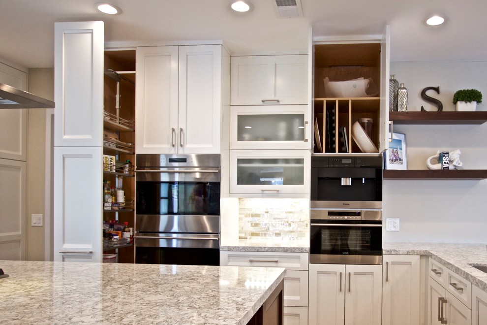 Inspiration for a transitional u-shaped open plan kitchen in Orange County with an undermount sink, recessed-panel cabinets, white cabinets, mosaic tile splashback, stainless steel appliances, medium hardwood floors, with island and brown floor.