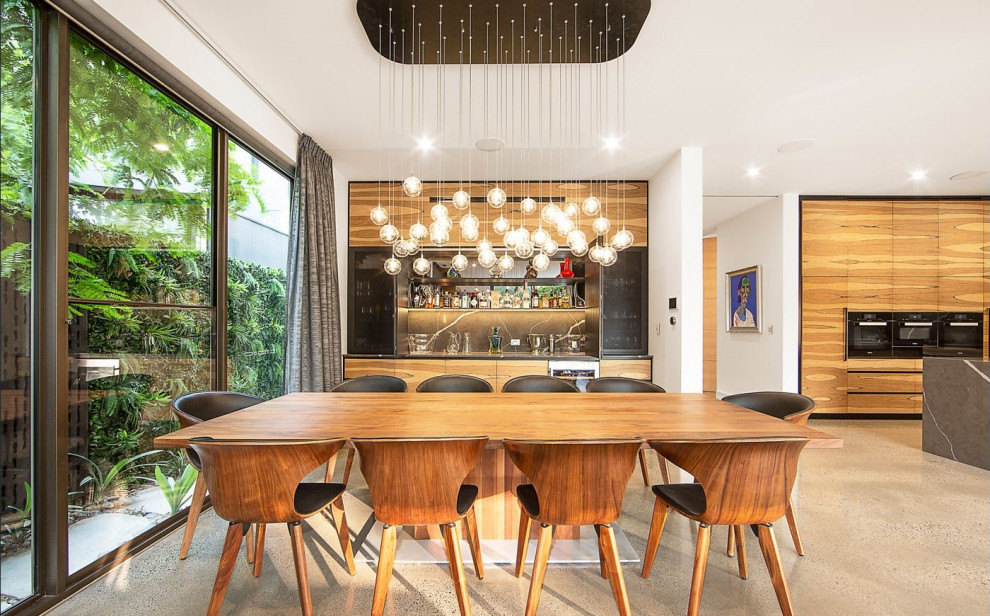 This is an example of a contemporary open plan dining in Melbourne with white walls, concrete floors, no fireplace and beige floor.