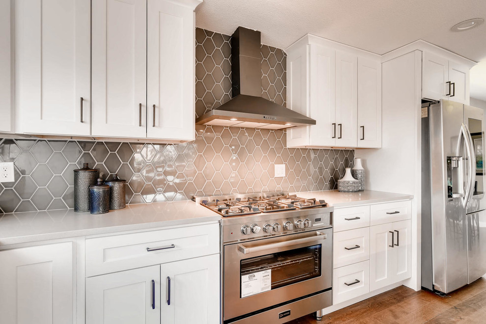 Inspiration for a large transitional l-shaped eat-in kitchen remodel in Denver with an undermount sink, shaker cabinets, white cabinets, quartz countertops, beige backsplash, ceramic backsplash, stainless steel appliances, an island and beige countertops