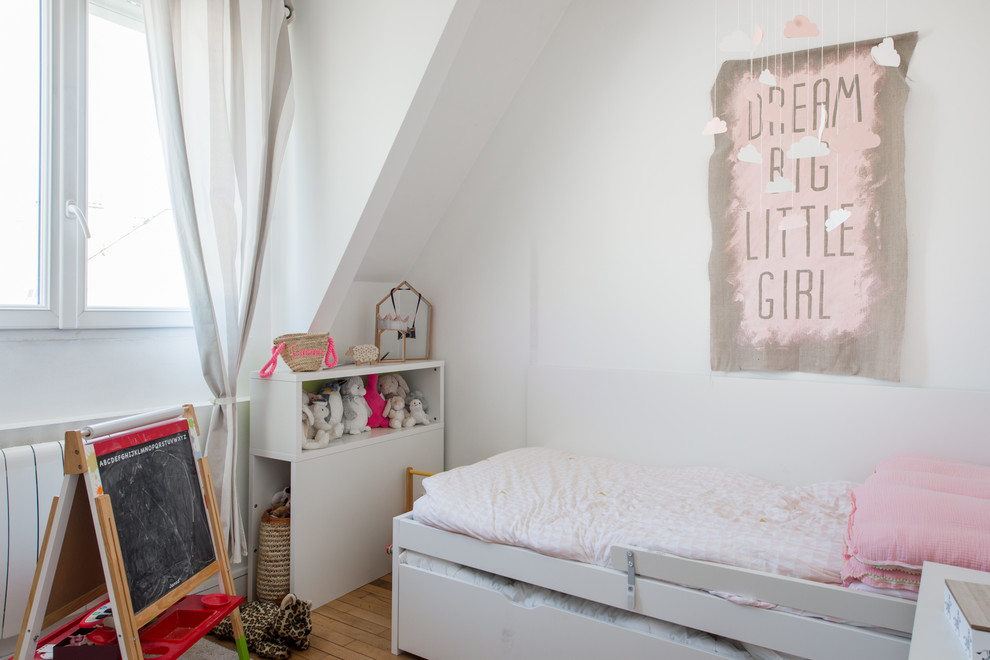 This is an example of a contemporary kids' bedroom for kids 4-10 years old and girls in Montpellier with white walls and light hardwood floors.