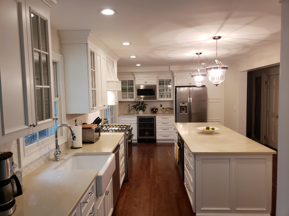 Large contemporary eat-in kitchen in New York with shaker cabinets, white cabinets, quartzite benchtops, white splashback, with island, brown floor and beige benchtop.