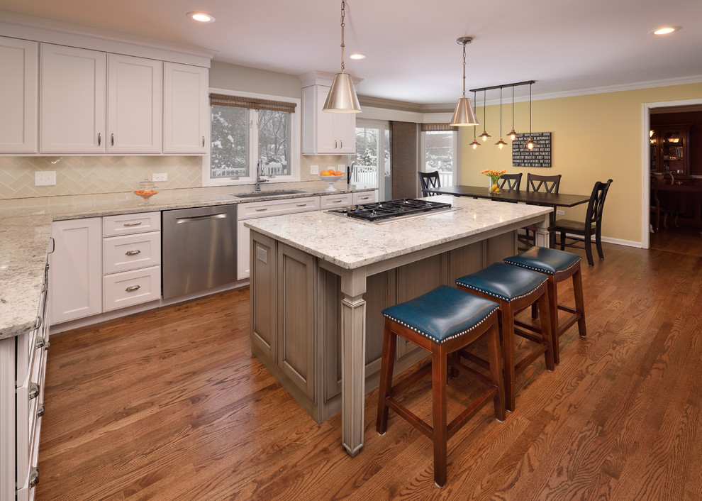 Open concept kitchen - large transitional l-shaped medium tone wood floor open concept kitchen idea in Chicago with an undermount sink, recessed-panel cabinets, white cabinets, granite countertops, gray backsplash, ceramic backsplash, stainless steel appliances and an island