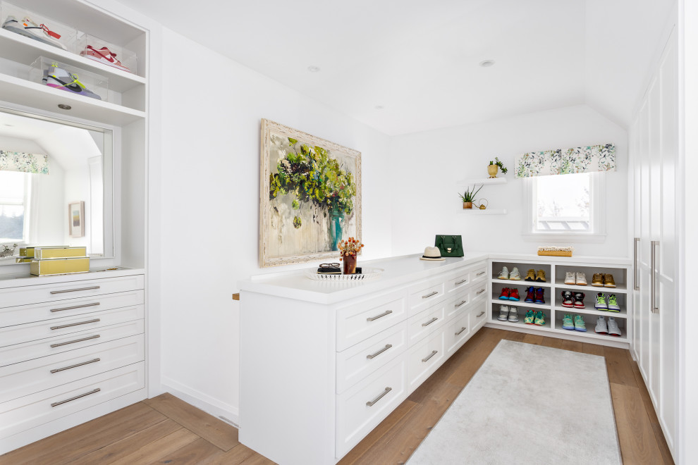 Inspiration for an expansive beach style gender-neutral walk-in wardrobe in Other with shaker cabinets, white cabinets, medium hardwood floors and brown floor.