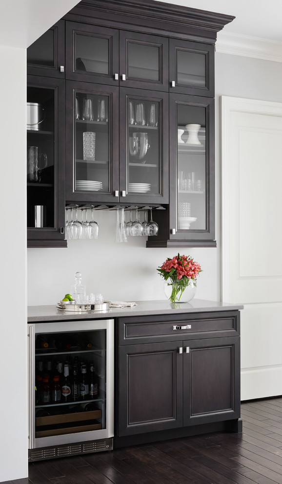 Inspiration for a small transitional home bar in Chicago with dark wood cabinets, quartz benchtops, dark hardwood floors, no sink and glass-front cabinets.