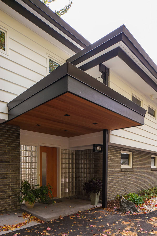 This is an example of a large midcentury split-level white exterior in Other with mixed siding and a flat roof.