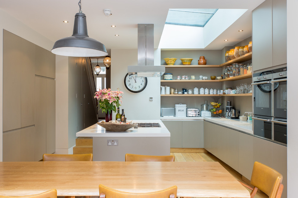 Design ideas for a large contemporary eat-in kitchen in London with flat-panel cabinets, grey cabinets, light hardwood floors and with island.