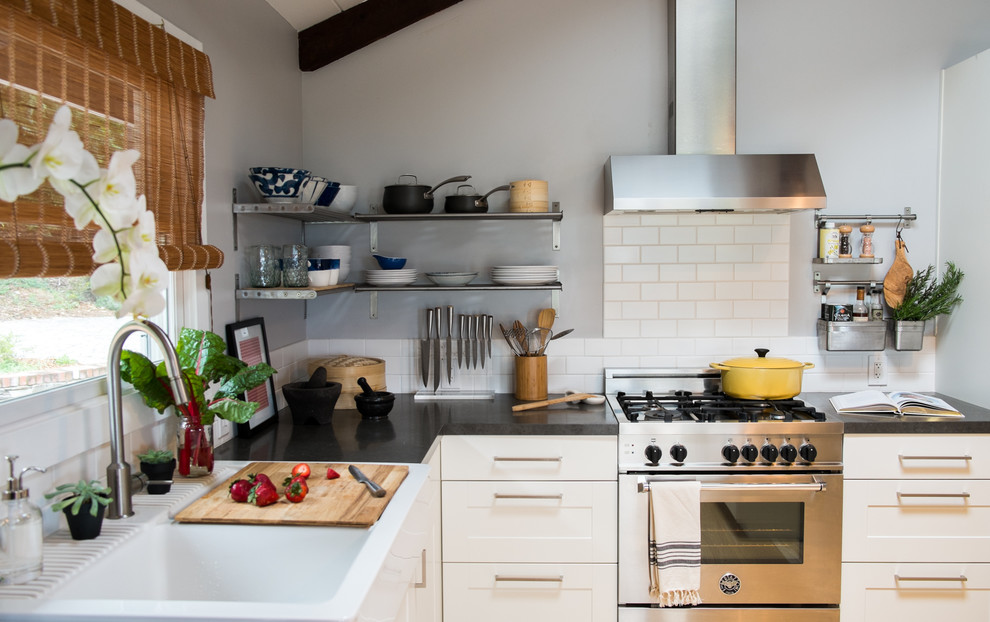 Inspiration for an eclectic light wood floor eat-in kitchen remodel in San Francisco with a farmhouse sink, shaker cabinets, white cabinets, quartz countertops, white backsplash, subway tile backsplash, stainless steel appliances and an island