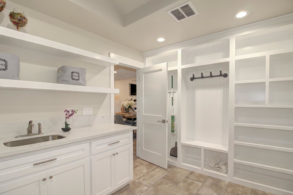 Photo of a mid-sized traditional utility room in Sacramento with an undermount sink, shaker cabinets, white cabinets, quartz benchtops, white splashback, engineered quartz splashback, grey walls, ceramic floors, a side-by-side washer and dryer, grey floor and white benchtop.