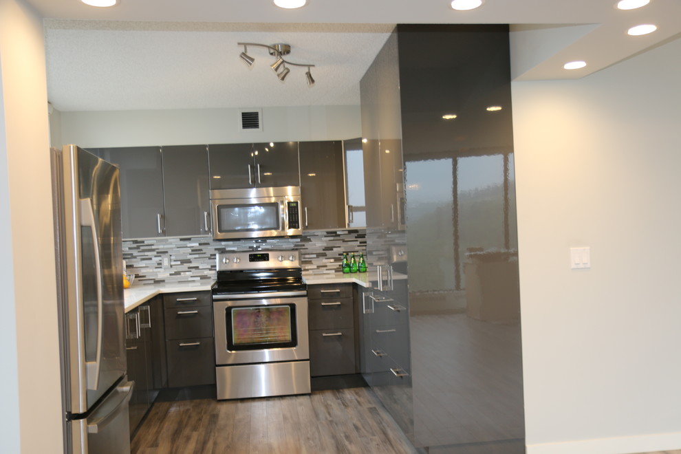 Inspiration for a mid-sized contemporary u-shaped light wood floor kitchen remodel with an undermount sink, flat-panel cabinets, gray cabinets, quartzite countertops, gray backsplash, glass tile backsplash and stainless steel appliances
