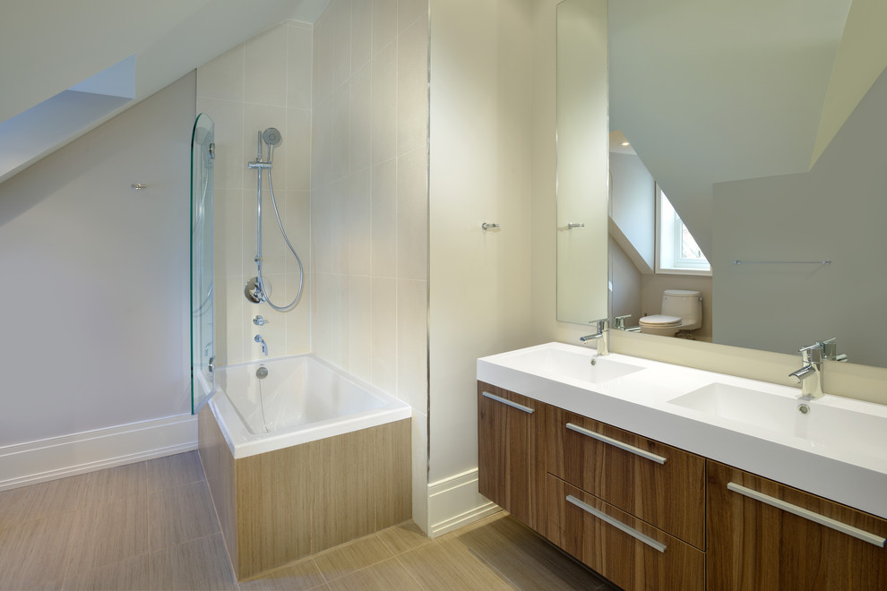 Design ideas for a mid-sized contemporary master bathroom in Toronto with an integrated sink, a shower/bathtub combo, flat-panel cabinets, light wood cabinets, porcelain tile, beige walls, porcelain floors, solid surface benchtops and a drop-in tub.