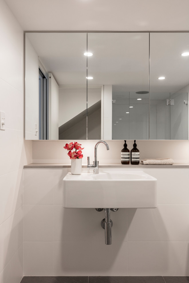 Small contemporary 3/4 bathroom in Sydney with an alcove shower, a wall-mount toilet, white tile, ceramic tile, white walls, ceramic floors and a wall-mount sink.